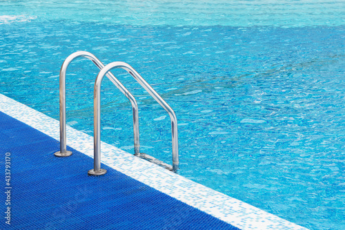 Metal railing in the pool for safety when descending into the water.Handrails for people in the public pool.