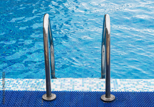 Metal railing in the pool for safety when descending into the water.Handrails for people in the public pool.