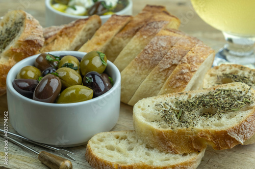 Rustic bread and pickled olives over wooden background. Mediterranean snacks.