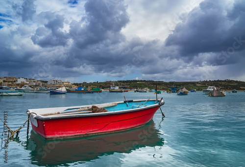 The old fishing boat is moored at the coast of Marsaxlokk village