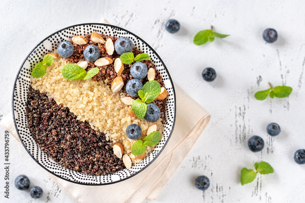 Bowl of  cooked quinoa with nuts and blueberries