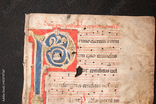 Fotografie A medieval manuscript hand written onto parchment or vellum and illuminated with red initial flourishes in pen
