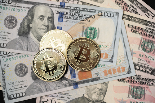 Metal shiny bitcoin crypto currency coins on US dollar bills. Electronic decentralized money concept.
