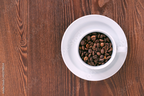 white cup  saucer and coffee beans on a wooden background