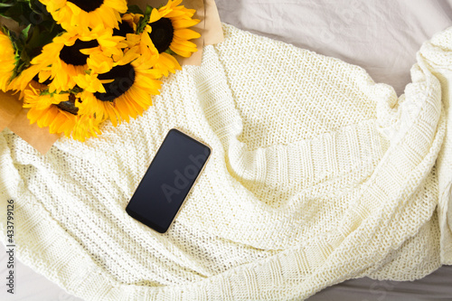 Bouquet of yellow sunflowers with phone on fabric white plaid background