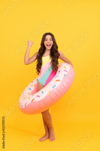 summertime kid weekend. summer vacation. amazed girl in swimsuit inflatable doughnut ring.