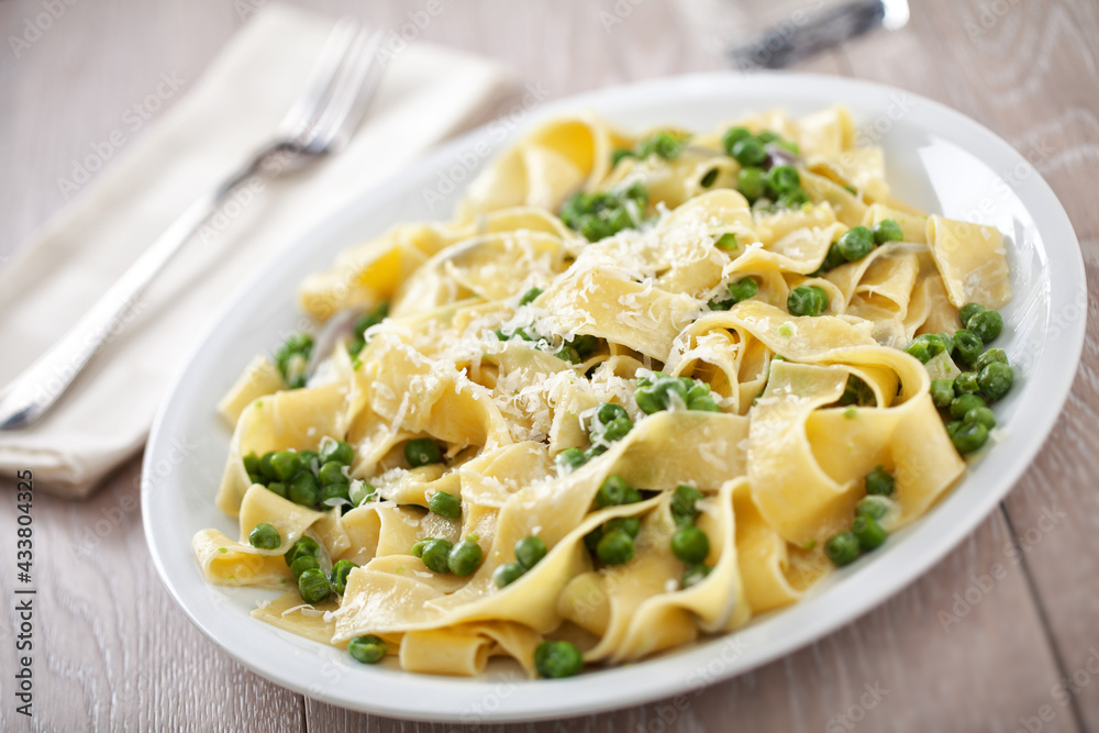 Tagliatelle pasta with cream and peas on a plate.