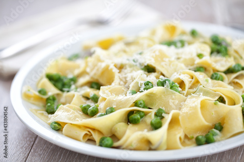 Tagliatelle pasta with cream and peas on a plate.