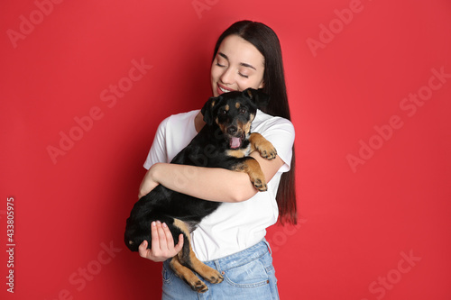 Young woman with cute puppy on red background photo