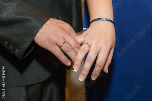 Gold rings displayed in the joined hands of the newlyweds, close up view.