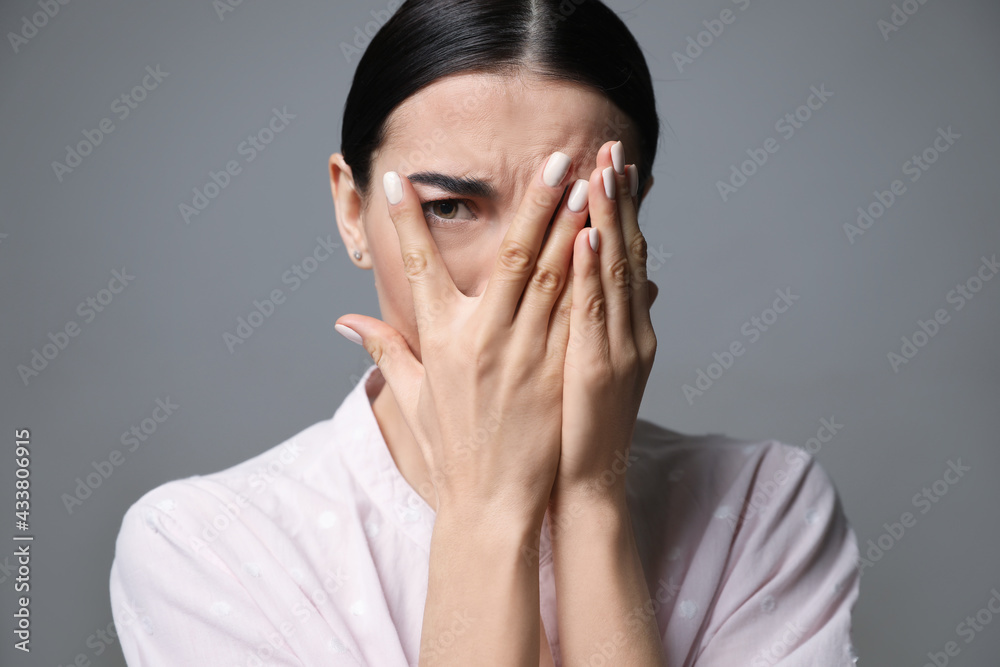 Young woman feeling fear on grey background, closeup Young woman feeling fear on grey background, closeup