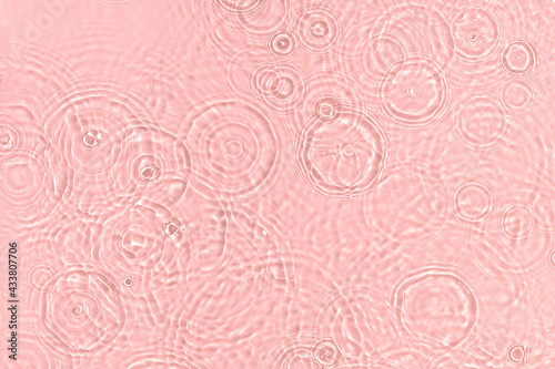 de-focused. Closeup of pink transparent clear calm water surface texture with ripples, splashes and bubbles. Trendy abstract summer nature background. Coral colored waves in sunlight.