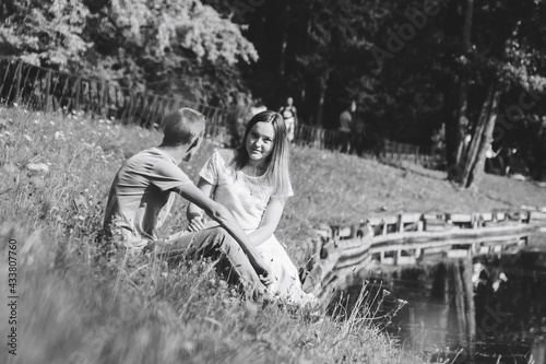 A happy young couple  a guy and a girl sitting on the grass near a river or lake