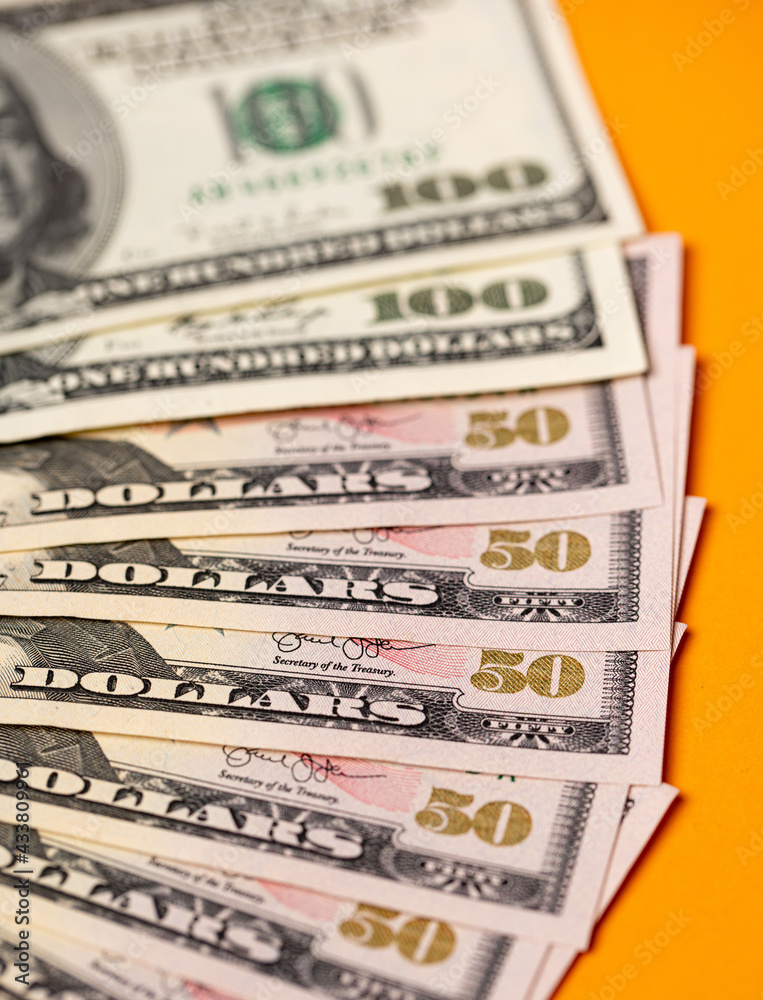 Fifty and one hundred dollar banknotes background. US dollar currency. President Grant and Franklin on dollar paper money with orange background Fifty and one hundred dollar banknotes background. US dollar currency. President Grant and Franklin on dollar paper money with orange background