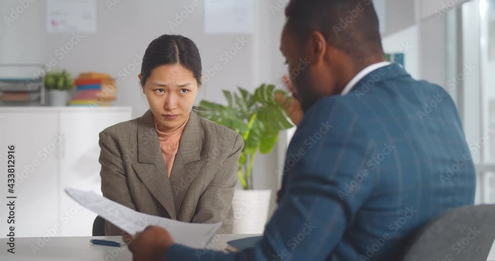 Angry african male boss shouting at young female employee pointing at report mistake Angry african male boss shouting at young female employee pointing at report mistake