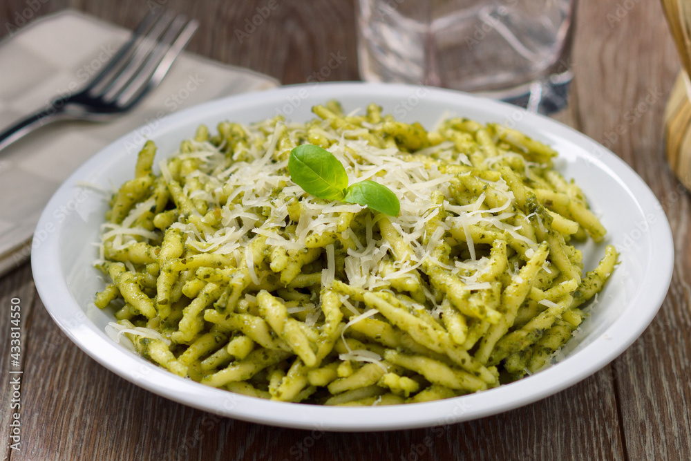 Pasta with pesto sauce and parmesan on a plate.