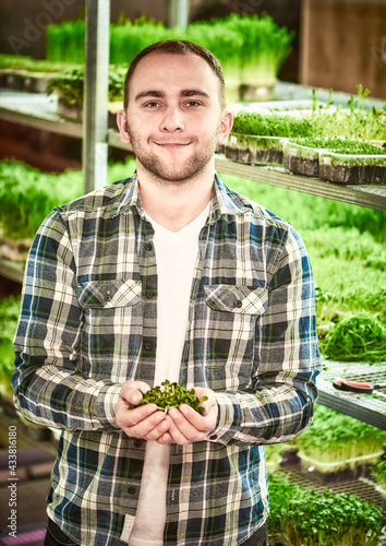 Portrait of a young man with seedlings of sunflower seeds in his hands in a greenhouse © Nikamata