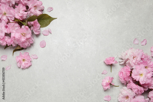 Beautiful sakura tree blossoms on grey stone table, flat lay. Space for text