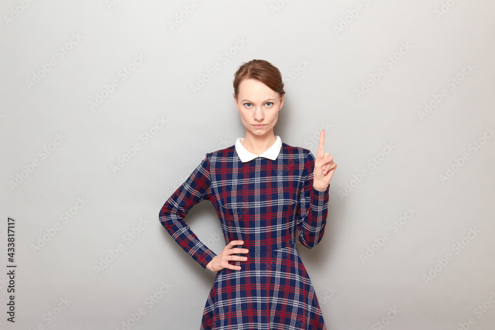 Portrait of serious young woman raising index finger up Portrait of serious young woman raising index finger up