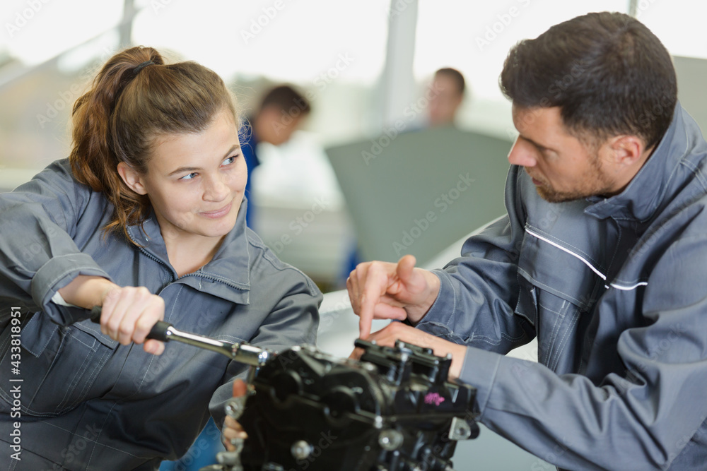 trainee female mechanic working on dismantled engine trainee female mechanic working on dismantled engine