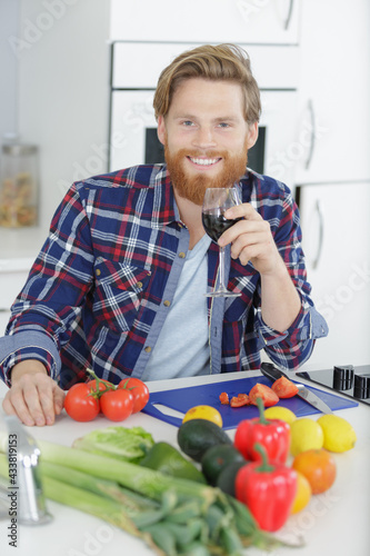 man preparing lunch in the kitchen while enjoying wine