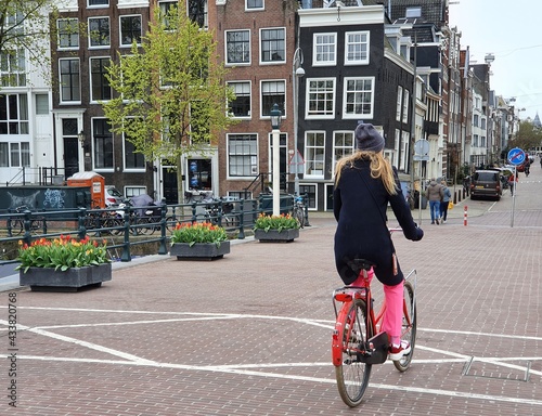 Amsterdam Skinny Bridge Street View with a Woman Wearing Pink Pants and a Black Coat on a Red Bicycle