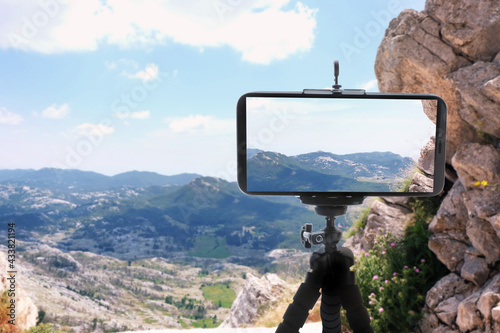 Taking photo of beautiful mountain landscape with smartphone mounted on tripod © New Africa