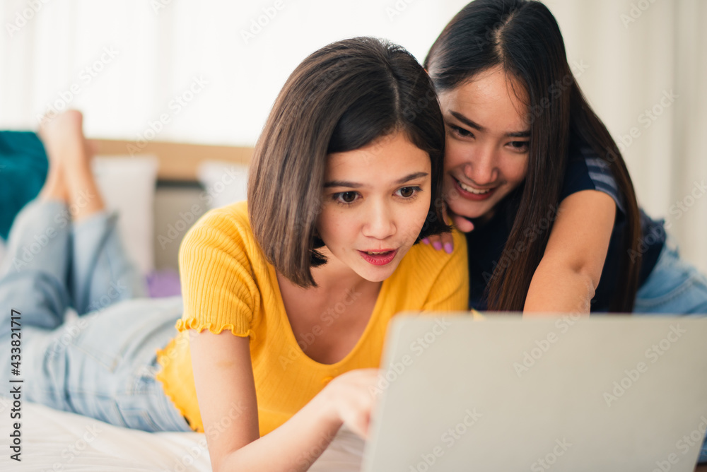 Young beautiful Asian couple love friend woman look at notebook on bed at hotel room when summer trip which smiling and felling happy, LGBT woman love Travelling summer vacation trip concept