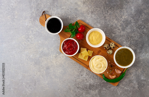 Set, assortment of sauces, ketchup, mayonnaise, cheese, soy, green, on a cutting board, with ingredients, on a gray table, top view, no people,