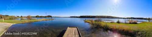 a gorgeous panoramic shot of a dirt footpath through the forest near the vast blue lake water with lush green and autumn colored trees along the lake at Lake Horton Park in Fayetteville Georgia photo