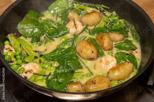 A delicious plate of potatoes fricassee with tiger prawns boiling and cooking in a pan