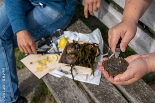 close up view of two caucasian women shucking raw oysters and enjoying them with lemon