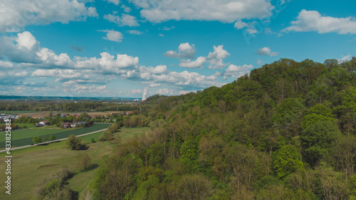 Landschaft in Deutschland mit Waldstück am Hang und Atomkraftwerk