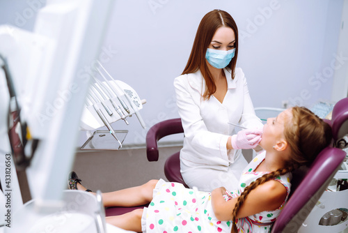 Little girl visiting dentists. Pretty girl opening his mouth wide during treating her teeth by the dentist.  Early prevention  oral hygiene and milk teeth care.