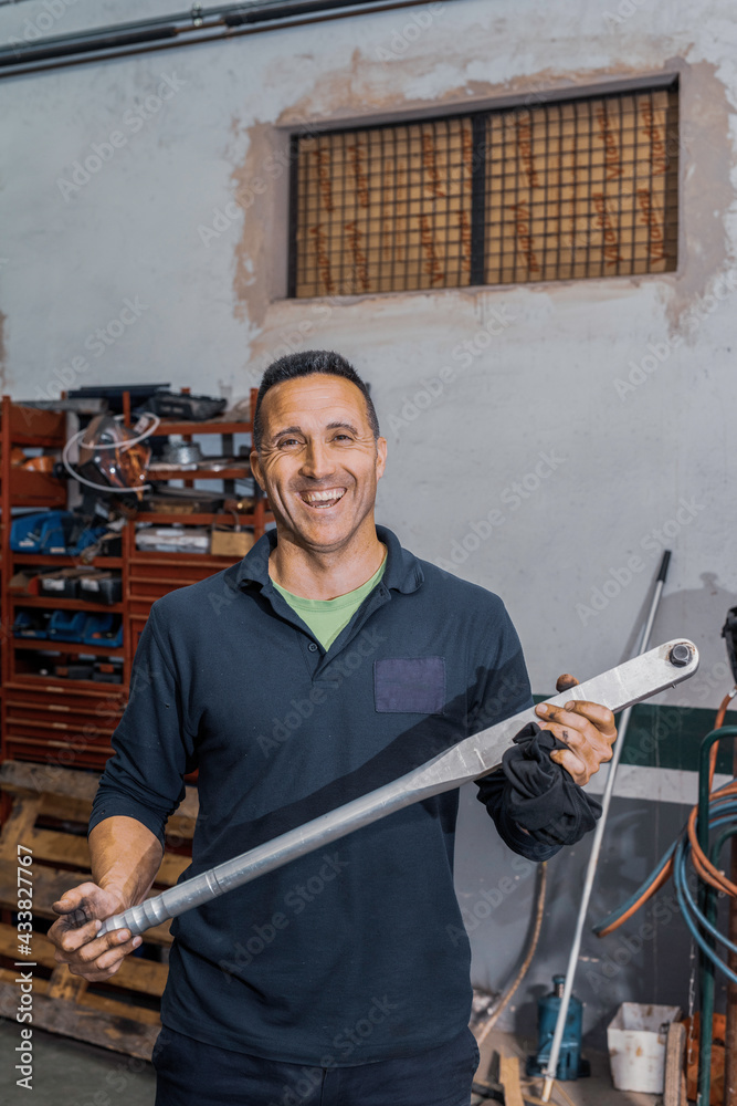 Caucasian mechanic standing smiling with torque wrench in his hands. Repair shop concept.