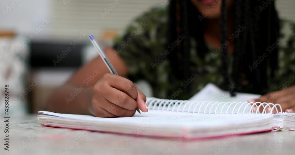 Black girl writing notes doing homework. preteen child studying
