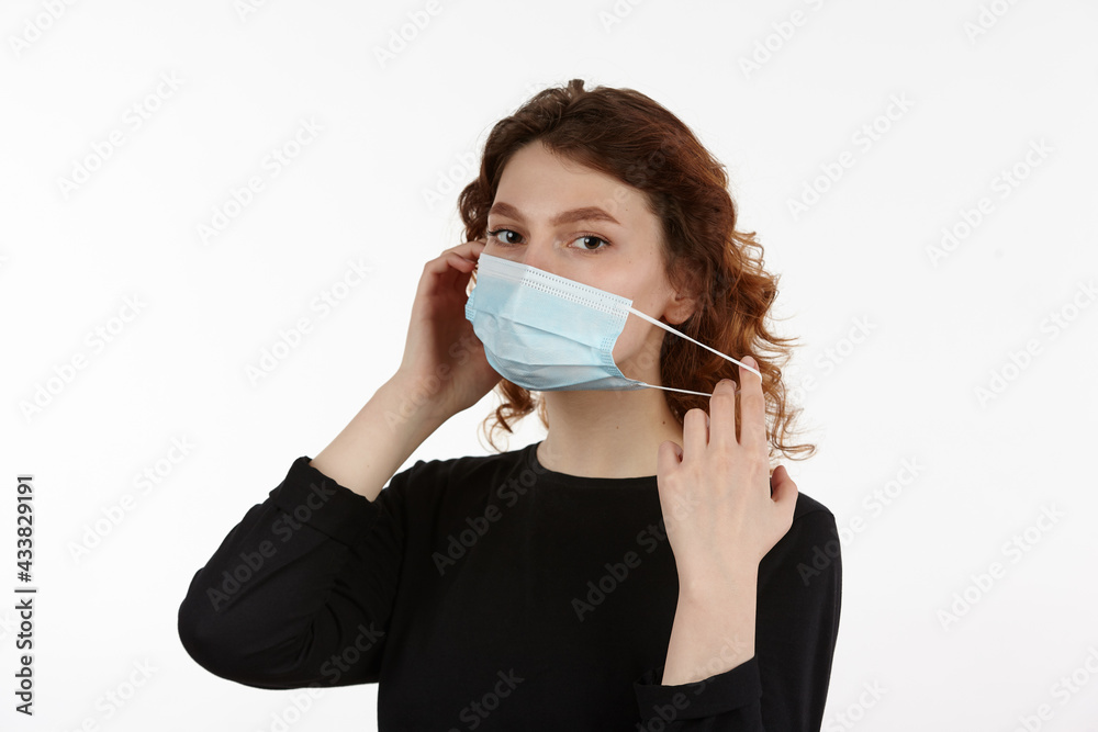 Young attractive girl in black clothes is wearing a medical protective mask to protect against coronavirus. Man isolated on white background. Young attractive girl in black clothes is wearing a medical protective mask to protect against coronavirus. Man isolated on white background.