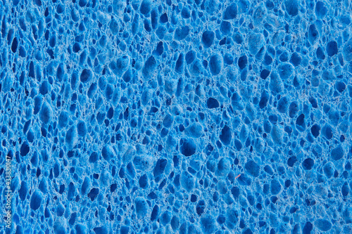 The porous structure of a blue washcloth with holes of different sizes on the surface, photographed in close-up