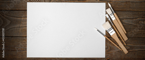 A clean white sheet and brushes on a wood textured background with space to copy.