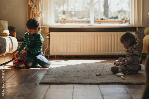 Fotografi Netherlandian kids on the floor playing separately with their own toys in a play