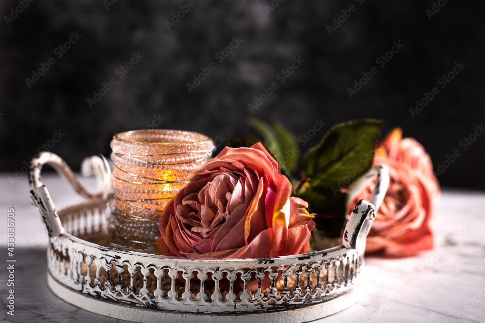 Drei Rosen in Alt Rose' Farben und ein Kerzenständer mit Perle liegen ...