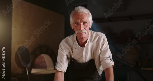 Senior italian bakery chef iwth freshly made pizza. Old small business owner. Professional chef in bakery shop looking at camera 4k footage photo