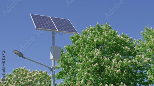 A street lamp and a solar panel against a blue sky.
