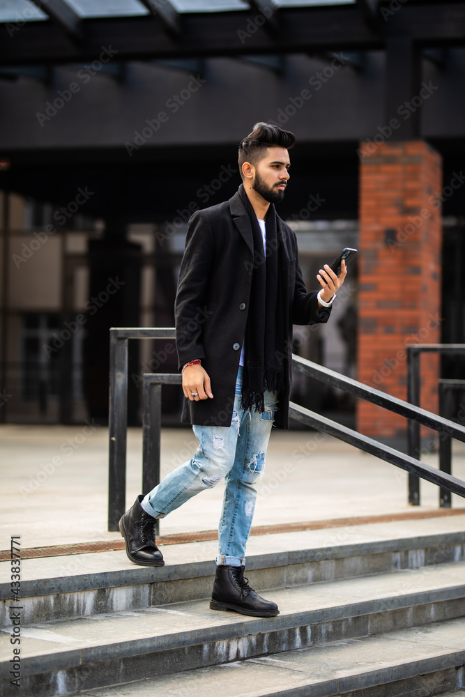 Handsome young businessman standing on the stairs while using his phone Handsome young businessman standing on the stairs while using his phone