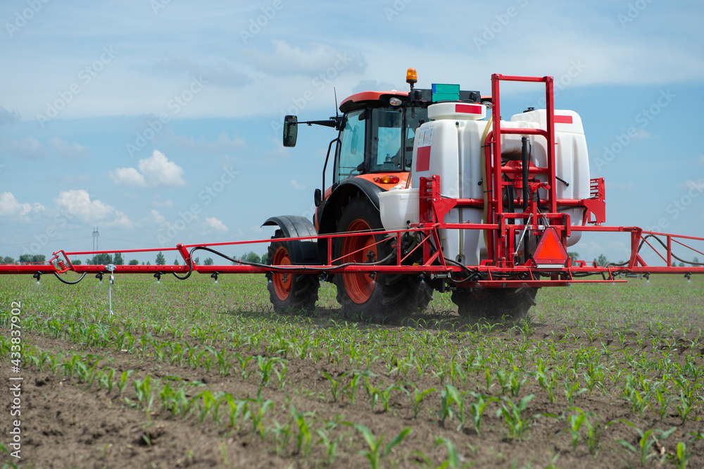 Tractor spraying pesticides at corn fields