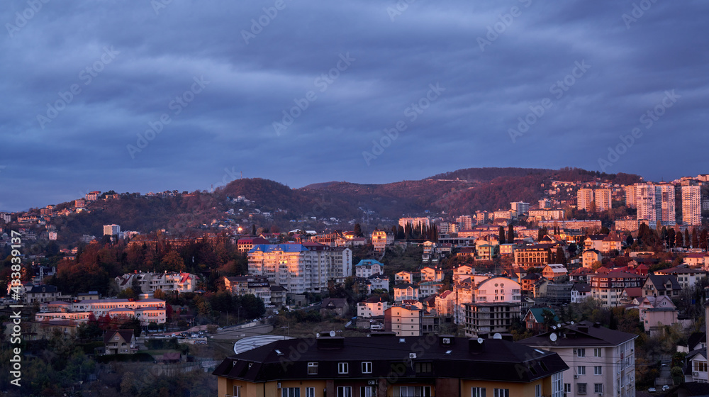 Panorama of the evening resort city Sochi, houses, mountains and sky. Summer urban landscape