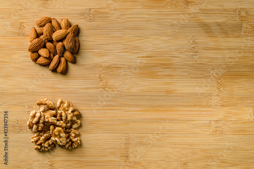 Raw almonds and walnut halves on the wooden cutting board background