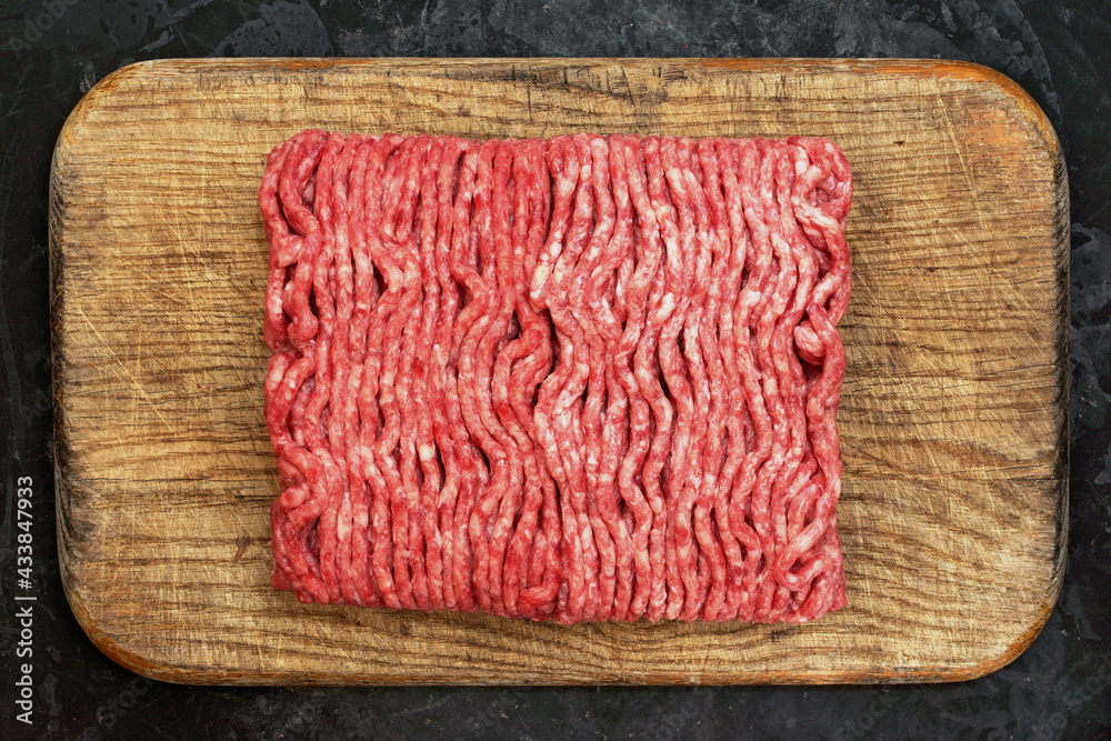 Cutting Board With Raw Minced Meat On Black Vintage Background. Top View Of Fresh Ground Beef Isolated On Black Background. Uncooked Minced Mixed Beef And Pork Meat On Old Cutting Board. Cutting Board With Raw Minced Meat On Black Vintage Background. Top View Of Fresh Ground Beef Isolated On Black Background. Uncooked Minced Mixed Beef And Pork Meat On Old Cutting Board.