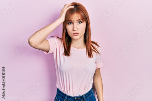 Redhead young woman wearing casual pink t shirt confuse and wonder about question. uncertain with doubt, thinking with hand on head. pensive concept.