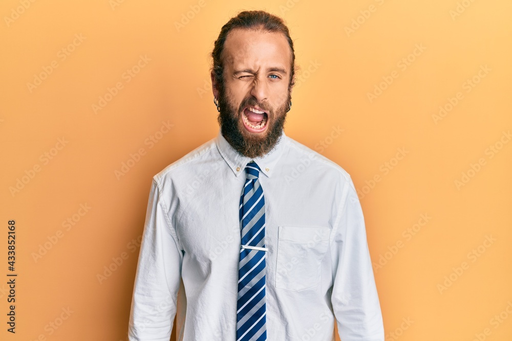Handsome man with beard and long hair wearing business clothes winking looking at the camera with sexy expression, cheerful and happy face.